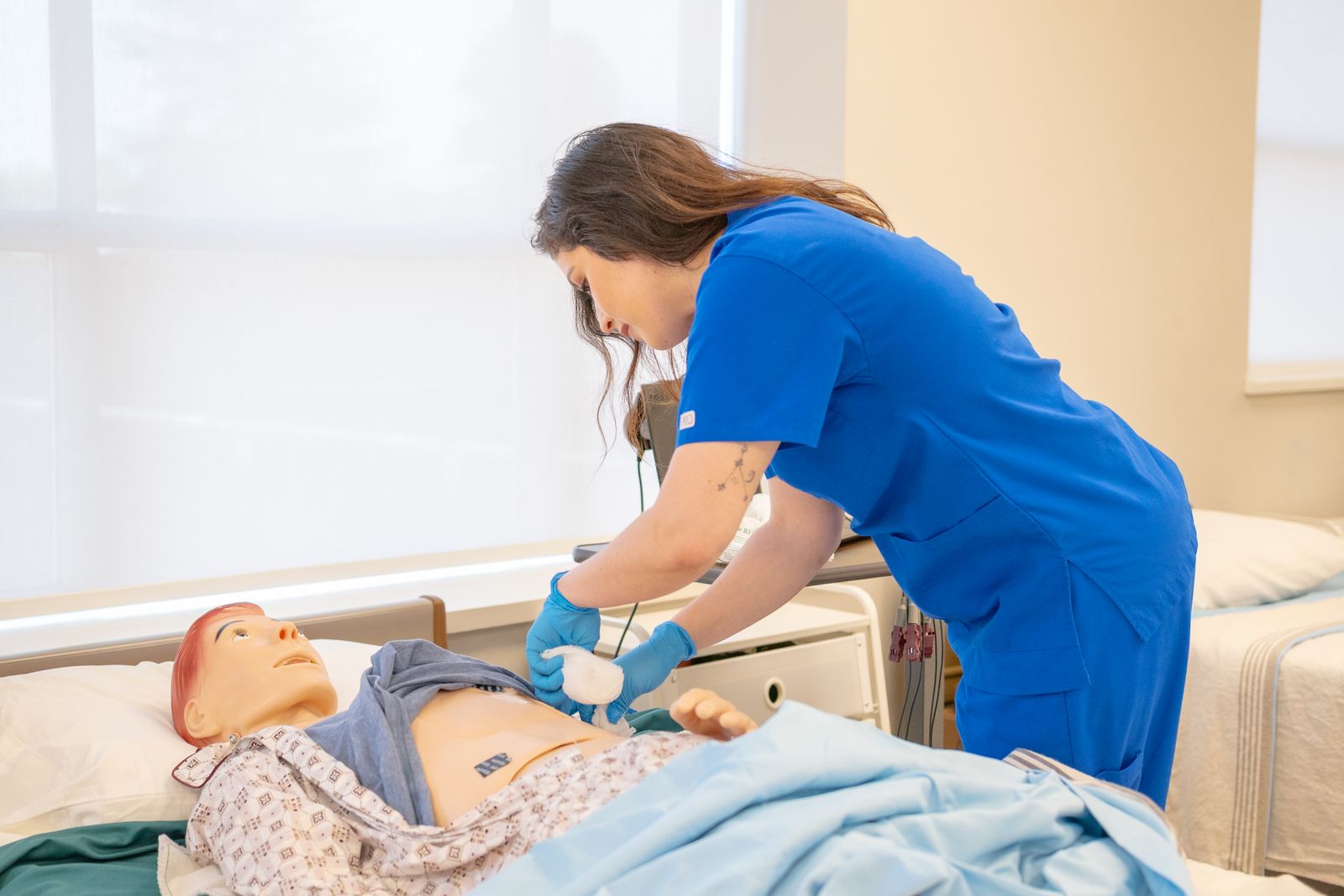 Nurse practicing clinical skills on a medical training manikin