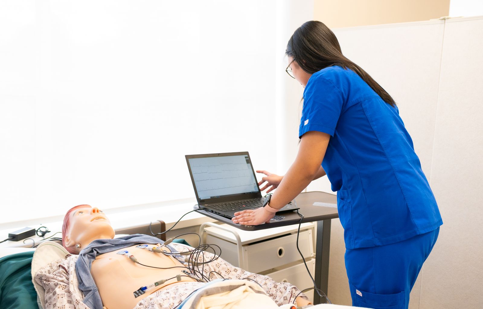 Healthcare professional practicing with a patient simulator in a clinical training room