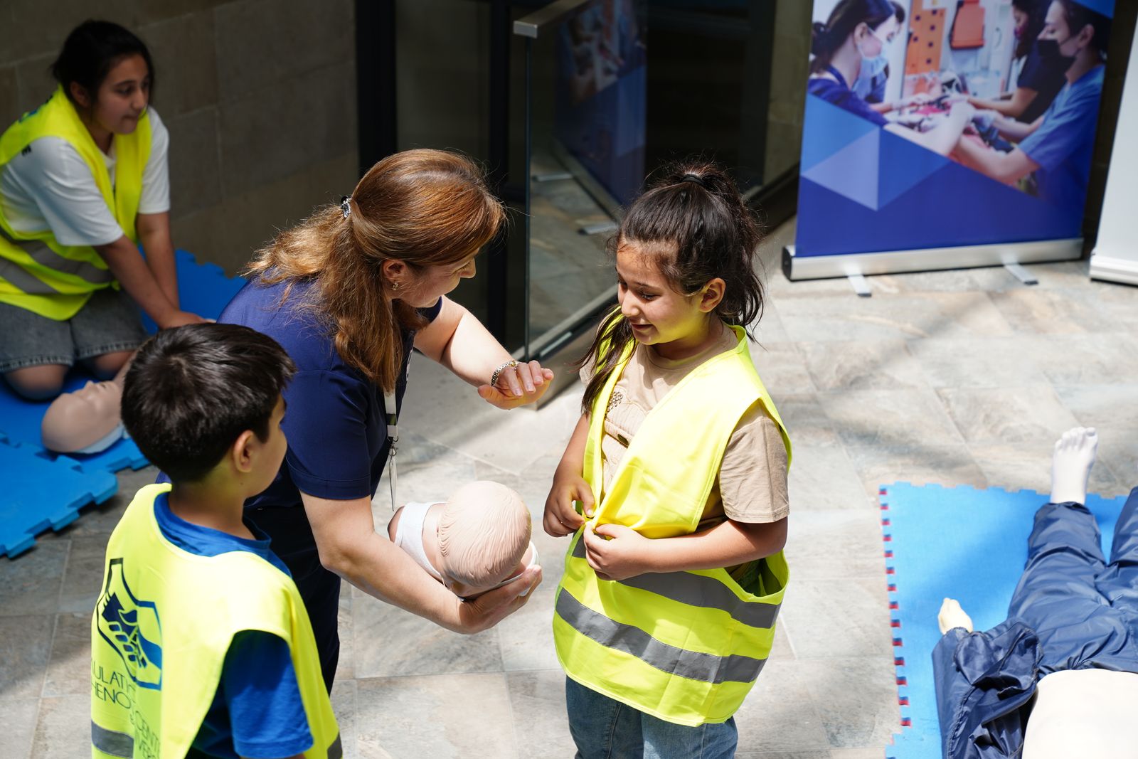 Childcare learners practicing CPR skills with an instructor and training manikin